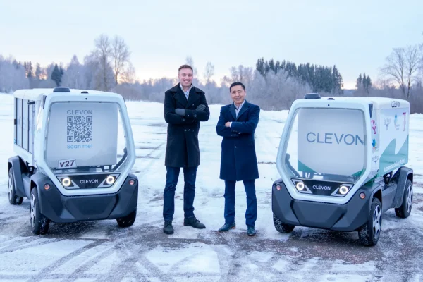 Clevon CEO Sander Sebastian Agur (left) and indiGO Technologies CEO Will Graylin (right) stand with the CLEVON 1 autonomous delivery robots following the companies’ merger.
